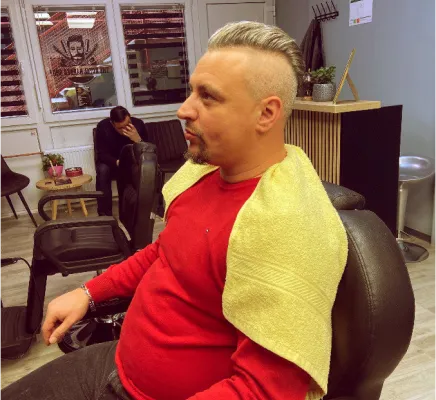 Klijent The Royal Barber Shopa u Sigetu sjedi u stolici nakon šišanja i gleda ispred sebe.