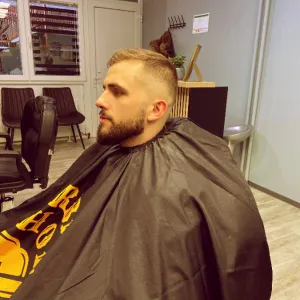 Klijent nakon frizure i održavanja brade u frizerskom salonu za muškarce